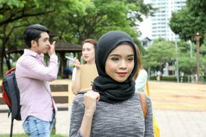 joven asiático malayo chino hombre mujer al aire libre parque libro archivo carpeta ordenador portátil computadora teléfono sentar estar estudiar mezclarse foto