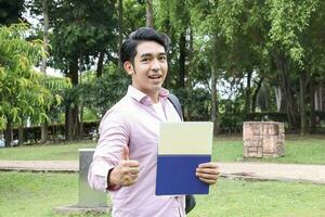 joven asiático malayo chino hombre mujer al aire libre parque caminar estar estudiar hablar discutir punto ordenador portátil archivo libro mochila masculino pulgares arriba foto