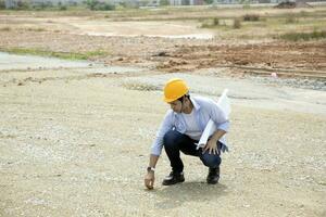 asiático hombre malayo trabajador ingeniero administración difícil la seguridad sombrero casco a construcción sitio comprobación suelo participación plan foto