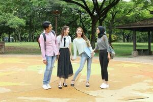 Young asian malay chinese man woman outdoor park walk stand study talk discuss point laptop file book backpack photo