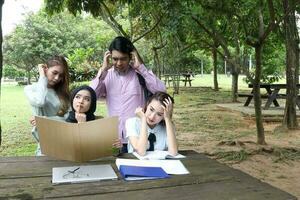 joven asiático malayo chino hombre mujer al aire libre parque libro archivo carpeta ordenador portátil computadora teléfono sentar estar estudiar mezclarse foto