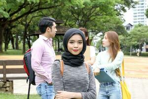 joven asiático malayo chino hombre mujer al aire libre parque caminar estar estudiar hablar discutir punto ordenador portátil archivo libro mochila hembra Mira adelante foto