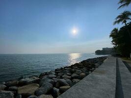 morning sunrise sea blue sky calm wave rocky shore Penang Malaysia photo
