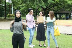 joven asiático malayo chino hombre mujer al aire libre parque libro archivo carpeta ordenador portátil computadora teléfono sentar estar estudiar mezclarse foto