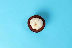 Purple mangosteen fruit pealed half on blue background photo