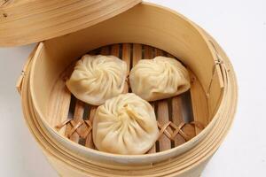 Xiao long bao dim sum dumpling chicken prawn fish seafood vegetable in bamboo steamer on white background photo