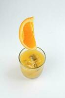 Fresh yellow orange juice in glass with whole floating sliced orange fruit and ice cube on white background photo