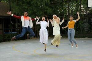 Group young asian chinese malay man woman wearing headscarf outdoor jump in the air happy exited photo
