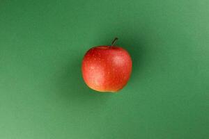 Red  apple on green colour paper background copy space for text photo