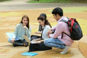 joven asiático malayo chino hombre mujer al aire libre parque libro archivo carpeta ordenador portátil computadora teléfono sentar estar estudiar mezclarse foto