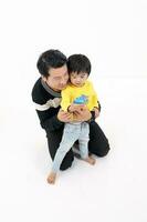 South East Asian father son child playing talking with phone toy tab on white background photo