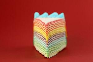 Rainbow crepe layer cake on red background photo