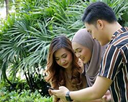 Young Asian Malay man woman outdoor green park walk talk discuss mingle photo