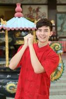 Young south east asian Chinese man woman traditional costume Chinese new year greeting outdoors at temple photo