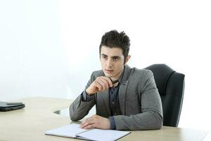 medio oriental caucásico joven oficina negocio hombre vistiendo traje sentar a oficina escritorio pensando planificación en blanco estudio antecedentes foto