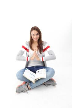 Yong Asian youth girl in casual dress sit on floor book on lap hand palm together yoga expression peace relaxed on white background photo