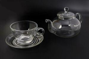 Empty transparent glass see through teapot kettle coffee tea cup saucer set on black background photo