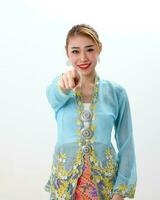 Asian woman traditional blue orange kebaya sharong on white  background pointing finger focus on finger photo