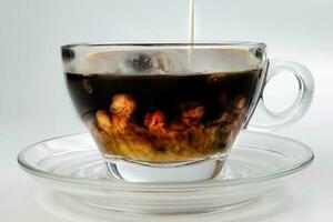 dark Coffee poring white milk dripping splash shadow liquid swirl in glass cup saucer on white background photo