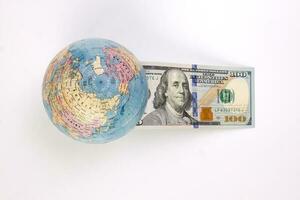 US Dollar currency paper money 100 Hundred dollar bill through planet earth globe on white background photo