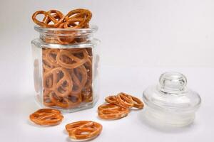 Pretzel cracker in a glass jar pouring dropping on white background photo