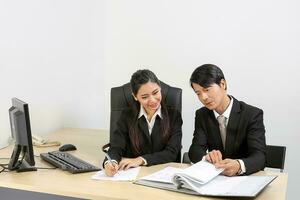 Young Asian male female wearing suit sitting at office desk thinking meeting disucsing sign document agreement photo