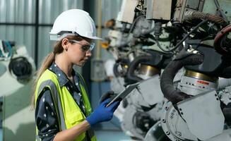 A female engineer installs a program on a robotics arm in a robot warehouse. And test the operation before sending the machine to the customer. photo