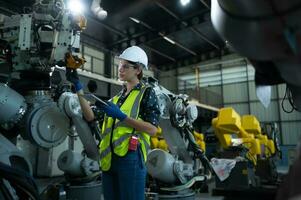 A female engineer installs a program on a robotics arm in a robot warehouse. And test the operation before sending the machine to the customer. photo