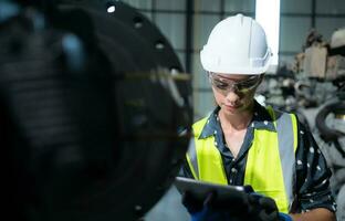 A female engineer installs a program on a robotics arm in a robot warehouse. And test the operation before sending the machine to the customer. photo