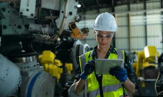 A female engineer installs a program on a robotics arm in a robot warehouse. And test the operation before sending the machine to the customer. photo