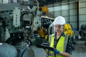 A female engineer installs a program on a robotics arm in a robot warehouse. And test the operation before sending the machine to the customer. photo