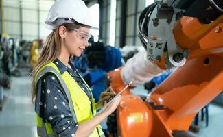 A female engineer installs a program on a robotics arm in a robot warehouse. And test the operation before sending the machine to the customer. photo
