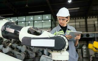 A female engineer installs a program on a robotics arm in a robot warehouse. And test the operation before sending the machine to the customer. photo