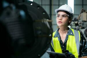 A female engineer installs a program on a robotics arm in a robot warehouse. And test the operation before sending the machine to the customer. photo