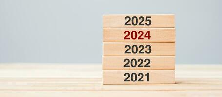 2025 bloquear terminado 2024 y 2023 de madera edificio en mesa antecedentes. negocio planificación, riesgo gestión, resolución, estrategia, solución, meta, nuevo año nuevo usted y contento fiesta conceptos foto