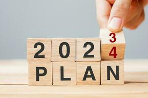 hand flipping block 2023 to 2024 PLAN text on table. Resolution, strategy, goal, motivation, reboot, business and New Year holiday concepts photo