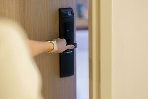 Hand using smart digital door lock while open or close the door at home or apartment. NFC Technology, Fingerprint scan, keycard, PIN number, smartphone, electrical and contactless lifestyle concepts photo