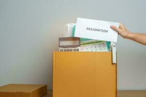 Resignation, Layoff, Unemployment, Dismiss, Job quit, Jobless and Farewell concept. Businesswoman holding letter of Resign contract with documents cardboard box at office photo