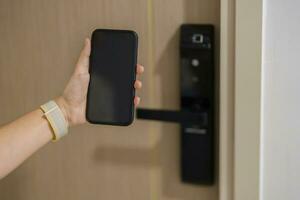 Hand using smartphone for open digital door lock at home or apartment. NFC Technology, Fingerprint scan, keycard, PIN number, smartphone, electrical and contactless lifestyle concepts photo