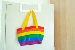 LGBT pride month concept or LGBTQ or LGBTQIA,Eco friendly bag with rainbow color hanging on the door. photo