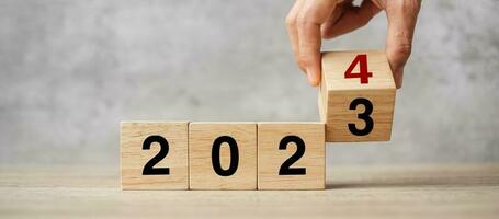 hand flipping block 2023 to 2024 text on table. Resolution, strategy, plan, goal, motivation, reboot, business and New Year holiday concepts photo