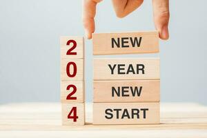 hand holding wooden block with text 2024 NEW YEAR NEW START on table background. Resolution, strategy, solution, business and holiday concepts photo