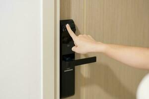 Hand using fingerprint scan for smart digital door lock while open or close the door at home or apartment. NFC Technology, keycard, PIN number, smartphone and contactless lifestyle concepts photo