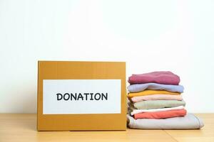 Donation, Charity, Volunteer, Giving and Delivery Concept. Clothes with Donation box at home or office for support and help poor, refugee and homeless people. Copy space for text photo