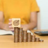 Money Saving for Future Plan, Retirement fund, budget, Goal and strategy Investment, Wealth Business and Financial concepts. Woman with Coins stack and dartboard block on table photo