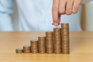 Money Saving for Future Plan, Retirement fund, Pension, Investment, Wealth Business and Financial concepts. hand putting coin into stack on table, Money counting and stack arrangement for deposit photo