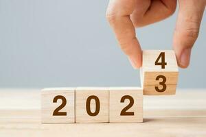 hand flip cube block 2023 to 2024 text on table. Resolution, review, strategy, end year, goal, business and New Year holiday concepts photo