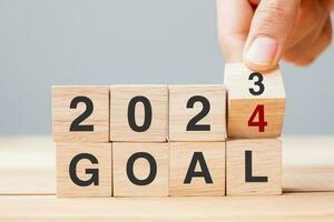 hand flipping block 2023 to 2024 GOAL text on table. Resolution, strategy, plan, motivation, reboot, business and New Year holiday concepts photo