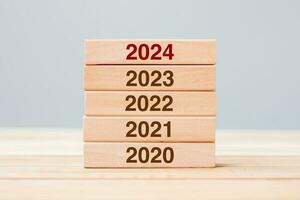 2024 bloque sobre 2023 y 2022 edificio de madera sobre fondo de mesa. planificación empresarial, gestión de riesgos, resolución, estrategia, solución, objetivo, nuevo año nuevo y felices conceptos de vacaciones foto