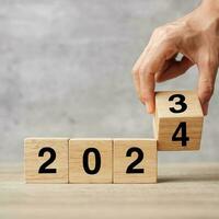 hand flipping block 2023 to 2024 text on table. Resolution, strategy, plan, goal, motivation, reboot, business and New Year holiday concepts photo